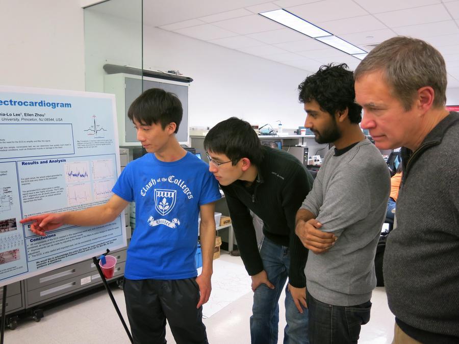 Student presenting in front of Professor Prucnal while other students listen